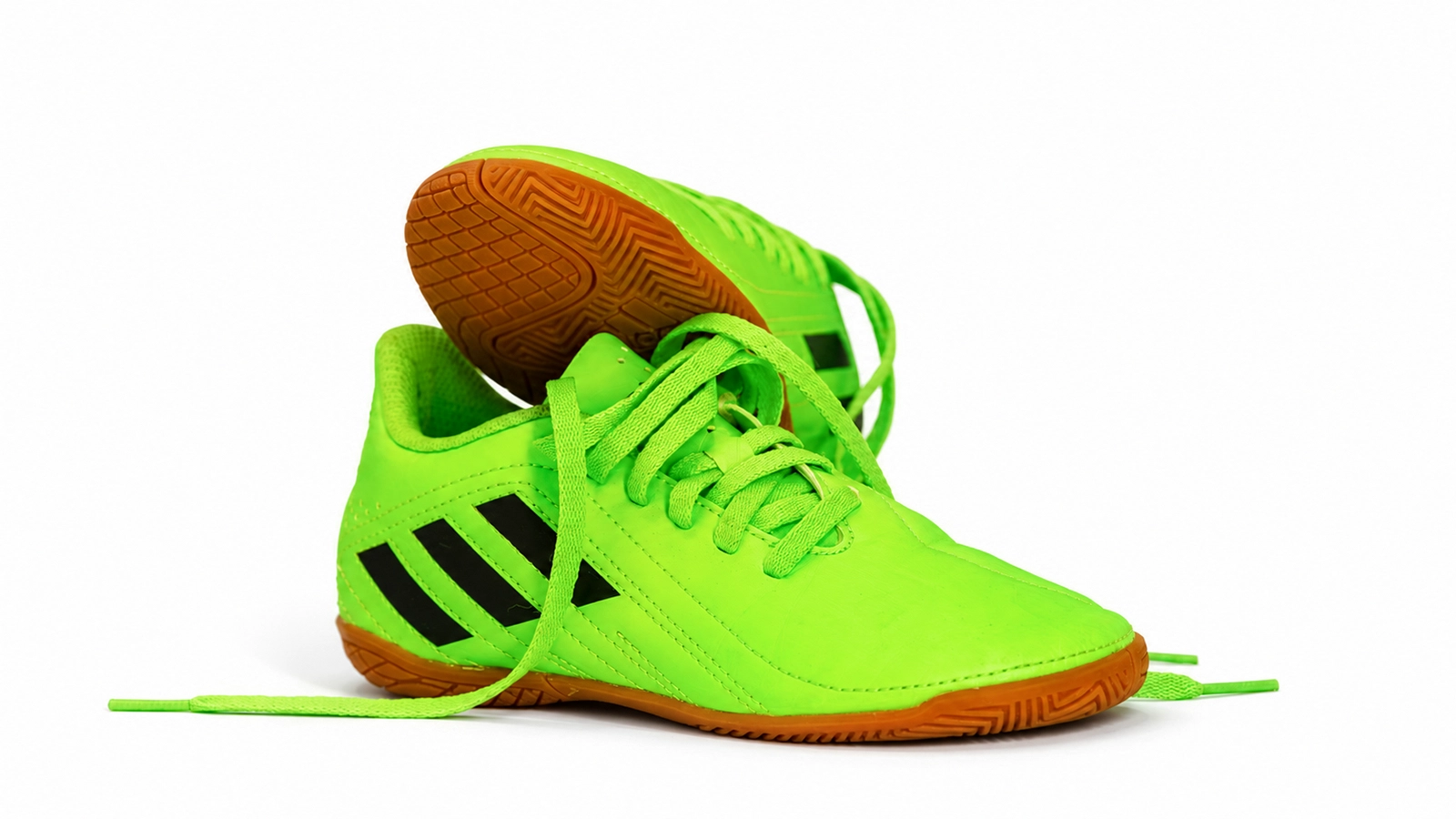 Freigestellter neonfarbener Fußballschuh auf weißem Hintergrund mit natürlichem Schatten als finales Ergebnis des Licht- und Farbtests.