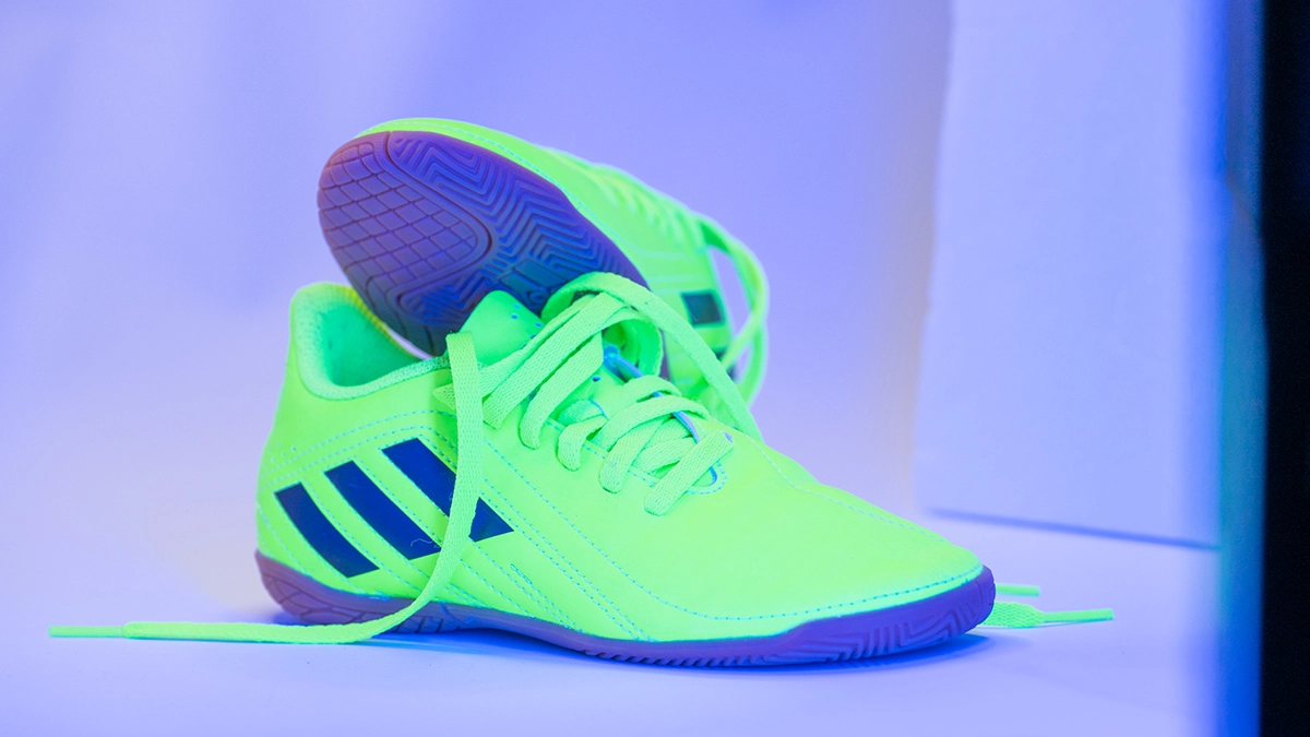 Neonfarbener Fußballschuh unter blau-violettem LED-Spektrum Neonfarbener Fußballschuh unter blau-violettem LED-Lichtspektrum mit deutlich veränderter Sohlen- und Schattenfarbe.