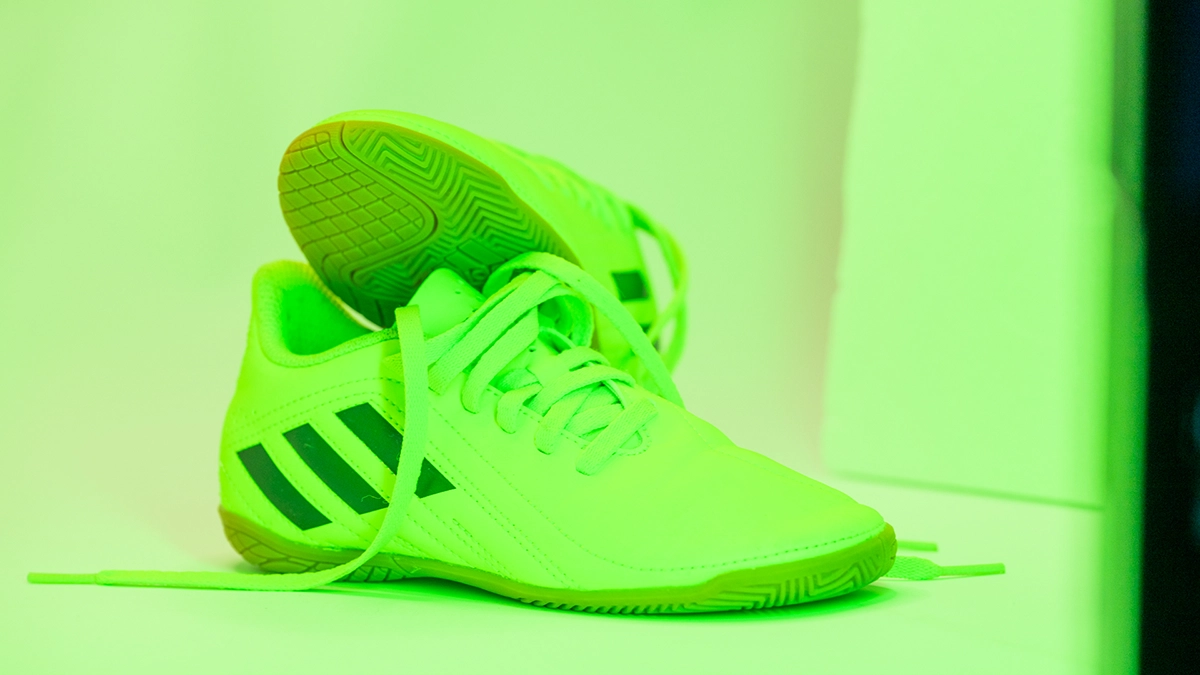 Neonfarbener Fußballschuh unter grünem LED-Spektrum Neonfarbener Fußballschuh unter grünem LED-Lichtspektrum mit stark grün beeinflusstem Hintergrund und Schatten.