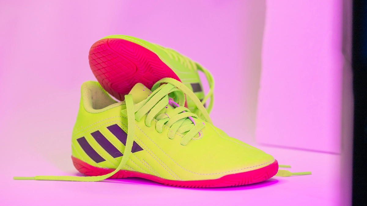 Neonfarbener Fußballschuh unter magentafarbenem LED-Spektrum Neonfarbener Fußballschuh unter magentafarbenem LED-Lichtspektrum mit grün wirkendem Obermaterial und pink verschobener Sohle.