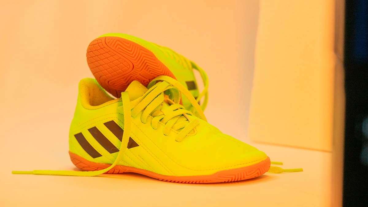 Neonfarbener Fußballschuh unter warmem LED-Spektrum Neonfarbener Fußballschuh unter warmem LED-Lichtspektrum mit gelb-orangefarbener Gesamtwirkung.