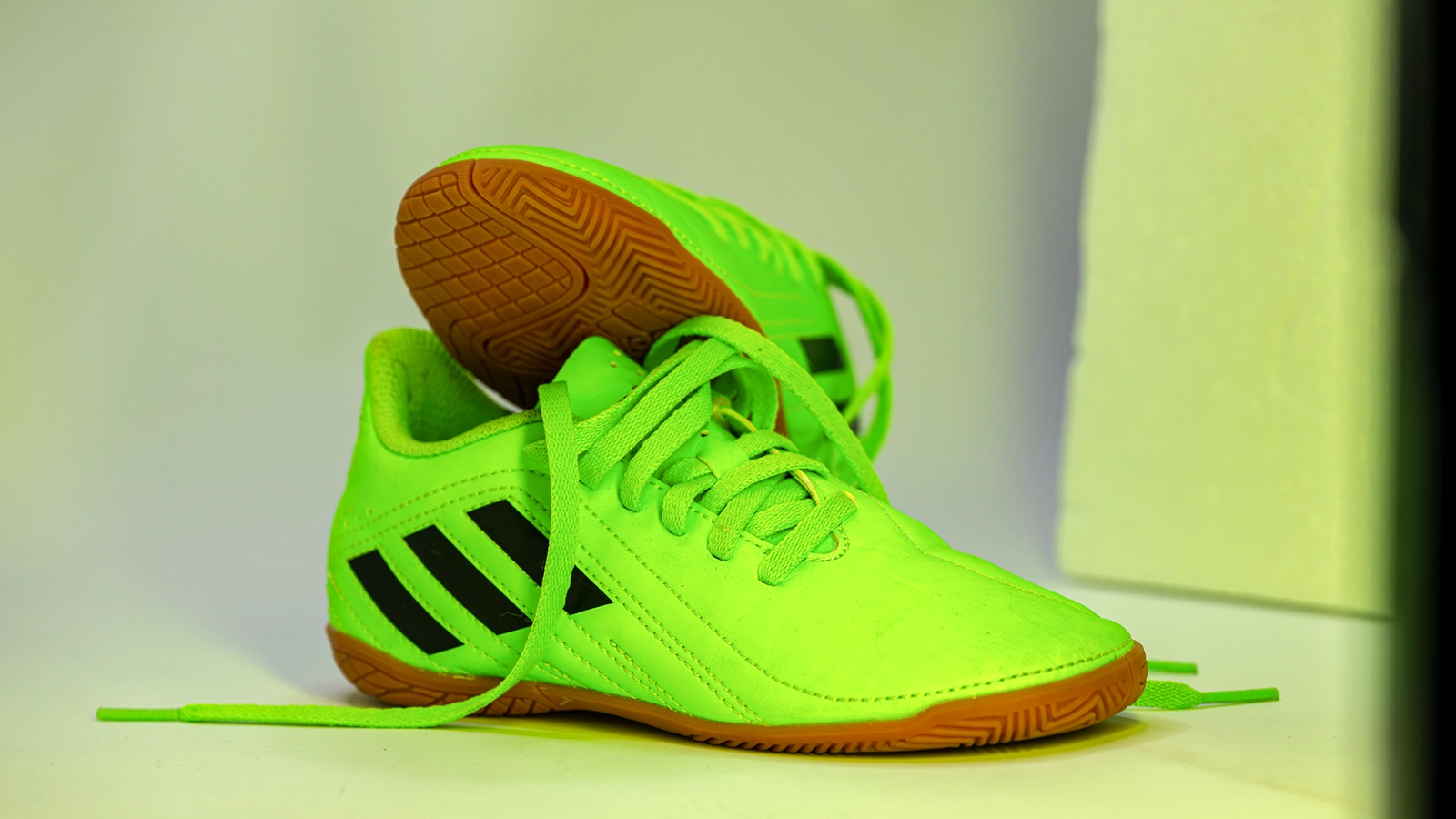 Neonfarbener Fußballschuh im tatsächlichen LED-Versuchsaufbau vor der Freistellung auf weißen Hintergrund.