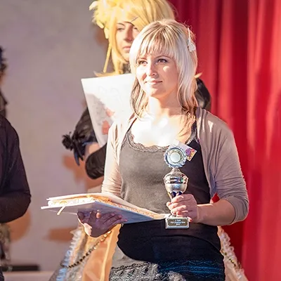 Gewinnerin eines Floristenwettbewerbs mit Pokal und Urkunde bei der Siegerehrung in Erfurt.