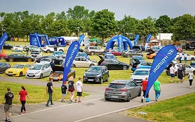 Hyundai Motorsport Treffen: Eventgelände mit Fahrzeugen, Besuchern und Hyundai-Bannern