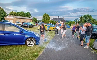 Motorsport-Treffen: Wasserschlacht nach der Siegerehrung mit Zuschauern und Fahrzeugen