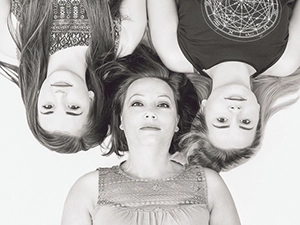 Schwarz-weißes Kopfporträt einer Mutter, die mit ihren zwei Töchtern auf dem Rücken liegt und die Köpfe sternförmig zur Mitte ausgerichtet sind. Ein zeitloses Familienporträt, perfekt für Ihre Familienfotografie in Erfurt von Michael Schalansky.