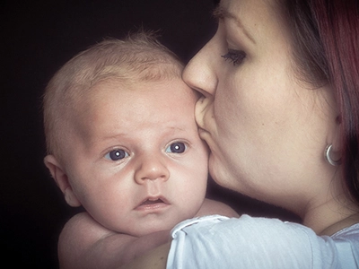 Zärtlicher Moment zwischen Mutter und Baby – Mutter küsst ihr Kind liebevoll im Porträt.