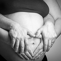 Hände der Eltern formen ein Herz auf dem Babybauch – emotionale Schwangerschaftsfotografie in Erfurt.