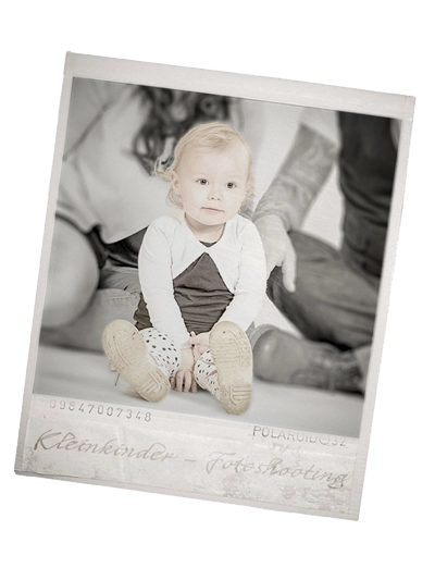 Polaroid-Kleinkinder-Fotoshooting in Schwarz-Weiß: Kleinkind sitzt frontal zur Kamera, Eltern im Hintergrund unscharf – emotionale Familienfotografie in Erfurt.