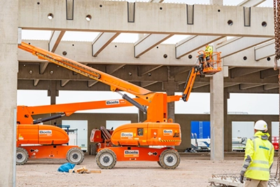 Baustellenfotografie: Zwei orange Boels Arbeitsbühnen in einer Industriehalle – Firmenfotografie von Michael Schalansky.