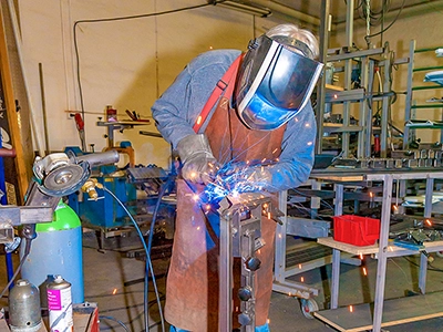 Industriefotografie in Thüringen: Schweißarbeiten mit Schutzhelm und Lichtbogen in einer Metallwerkstatt.