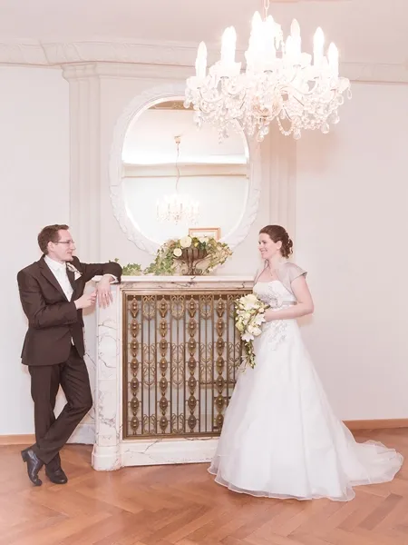 Farbiges Hochzeitsporträt eines Brautpaares vor einem prunkvollen Kamin – Hochzeitsfotografie von Michael Schalansky.