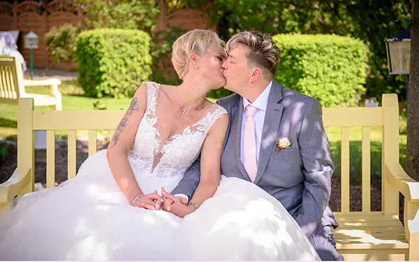 Hochzeitsfotografie in Erfurt und Thüringen: Brautpaar küsst sich auf einer Gartenbank im Grünen – emotionaler Moment von Michael Schalansky.