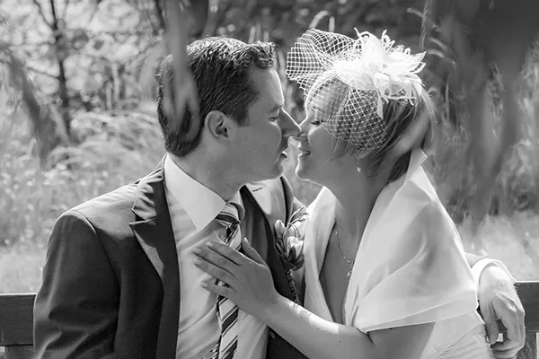 Schwarz-Weiß-Nahaufnahme eines Hochzeitskusses: Braut und Bräutigam kurz vor dem Kuss, inniger Moment im Grünen – Hochzeitsfotografie von Michael Schalansky in Erfurt und Thüringen.