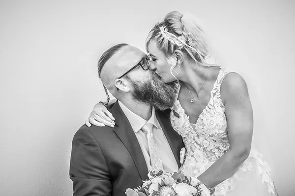 Schwarz-Weiß-Nahaufnahme eines Brautpaars beim Kuss, Braut im Spitzenkleid mit Strauß, Bräutigam mit Bart – Hochzeitsfotografie von Michael Schalansky in Erfurt und Thüringen.