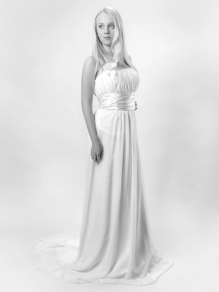 Elegantes_Hochzeitskleid_Braut_Studioaufnahme Schwarz-Weiss-Ganzkörperporträt einer jungen Frau in einem trägerlosen, bodenlangen Hochzeitskleid mit gerafftem Oberteil und fließendem Rock. Sie blickt nach links. Das Bild ist eine elegante Studioaufnahme, die die Schönheit des Hochzeitskleides und der Brautmode hervorhebt. Ein Beispiel für Porträt- und Brautmodefotografie von Michael Schalansky.