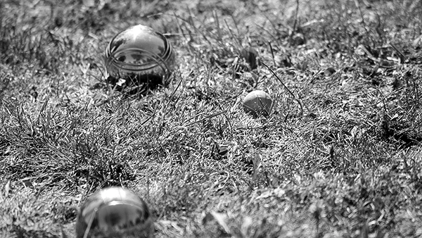 Szene eines Boule-Spiels mit mehreren Kugeln im kurz geschnittenen Gras, aus einer niedrigen Perspektive fotografiert, die die Dynamik des Spiels einfängt, festgehalten von Michael Schalansky.
