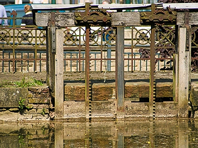 Nahaufnahme der Texturen von altem, verwittertem Holz und rostigem Eisen an einem historischen Wehr, das die Spuren der Zeit zeigt, ästhetische Detailaufnahme von Michael Schalansky.