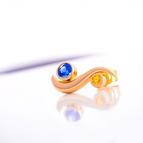 Goldener Ohrring mit blauem Edelstein – Produktfoto Produktaufnahme: Goldener Ohrring mit blauem Edelstein auf spiegelnder Oberfläche.