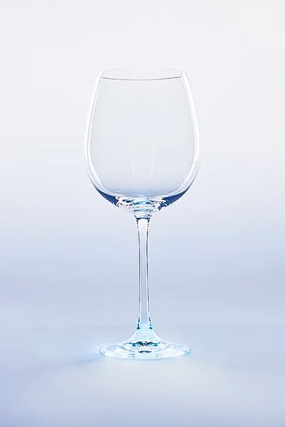 Perfekte Glasfotografie: Weinglas mit faszinierendem Lichtspiel. Inszenierung für Ihre Produkte im E-Commerce. Elegantes, leeres Weinglas mit feinen Lichtreflexen und blauer Schattierung auf hellem Hintergrund. Beispiel für brillante Glasfotografie.