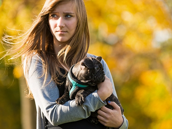 Ein zärtlicher Moment: Meine Aufnahme einer jungen Frau, die einen Hund liebevoll auf dem Arm hält, mit warmen Herbstfarben im Hintergrund.