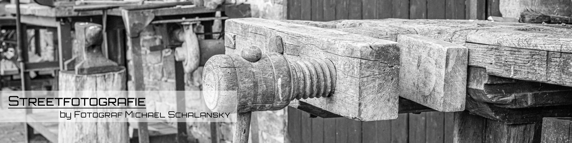 Schwarz-Weiß-Banner einer alten Holzwerkbank mit Schraubstock und Werkstattdetails – Streetfotografie von Michael Schalansky.