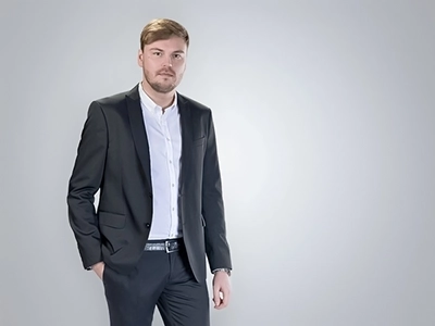 Professionelles Bewerbungsfoto eines Mannes im dunklen Anzug vor hellem Studiohintergrund.